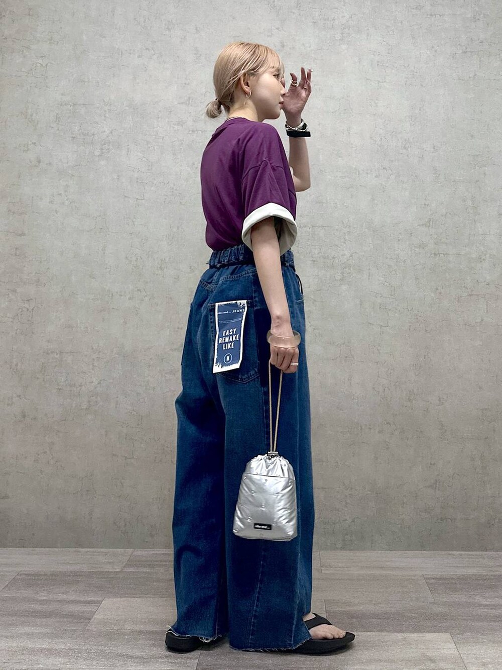 シルバー系のショルダーバッグ、パープル系のTシャツ/カットソー、ブルー系のデニムパンツを着用したレディースの春コーディネートの2枚目の写真