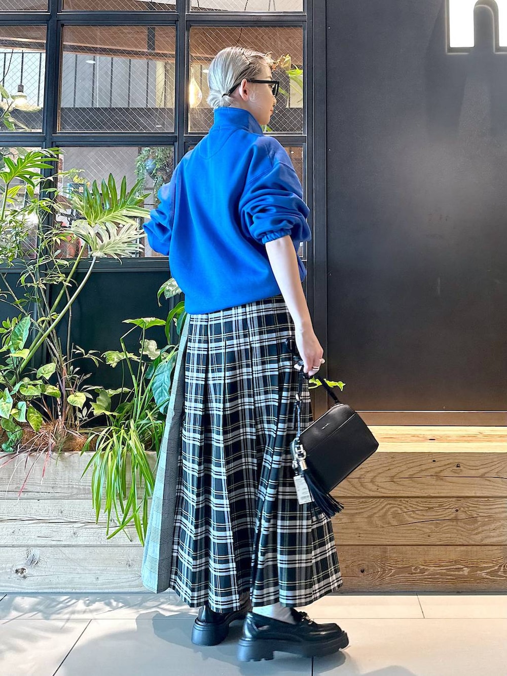 ホワイト系のスカート、ブラック系のショルダーバッグ、ブラック系のローファーを着用したレディースの秋コーディネートの2枚目の写真