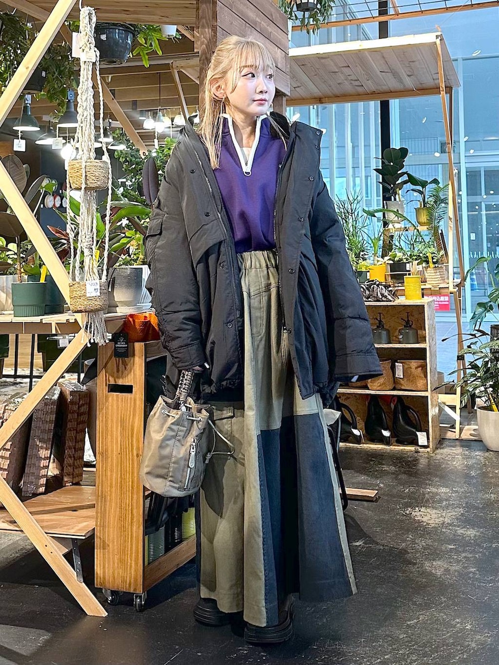 ブラック系のブルゾン、ブラウン系のブーツ、パープル系のスウェットを着用したレディースの冬コーディネートの4枚目の写真