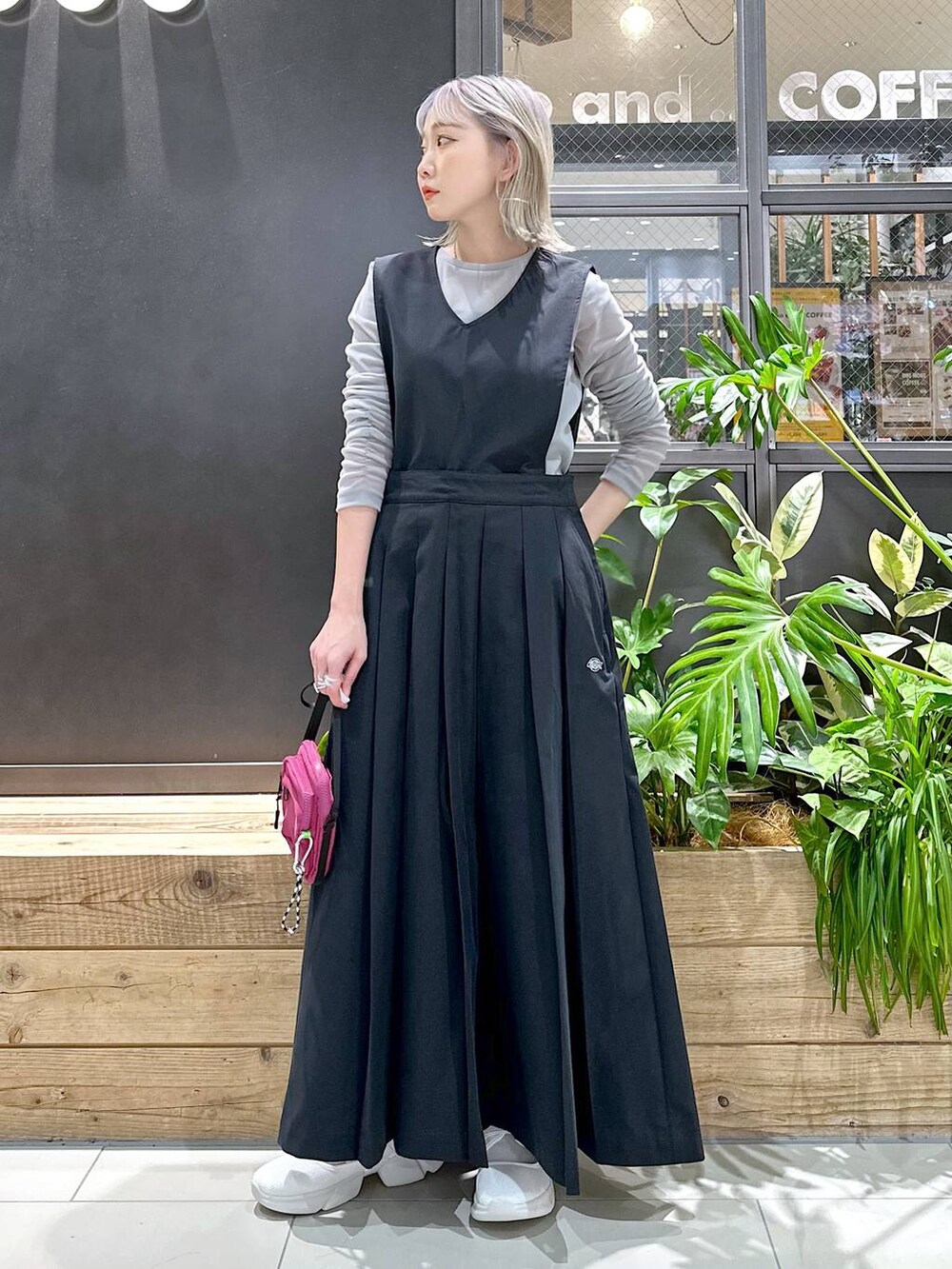 パープル系のショルダーバッグ、ベージュ系のスニーカー、ブラック系のジャンパースカートを着用したレディースの秋コーディネートの2枚目の写真