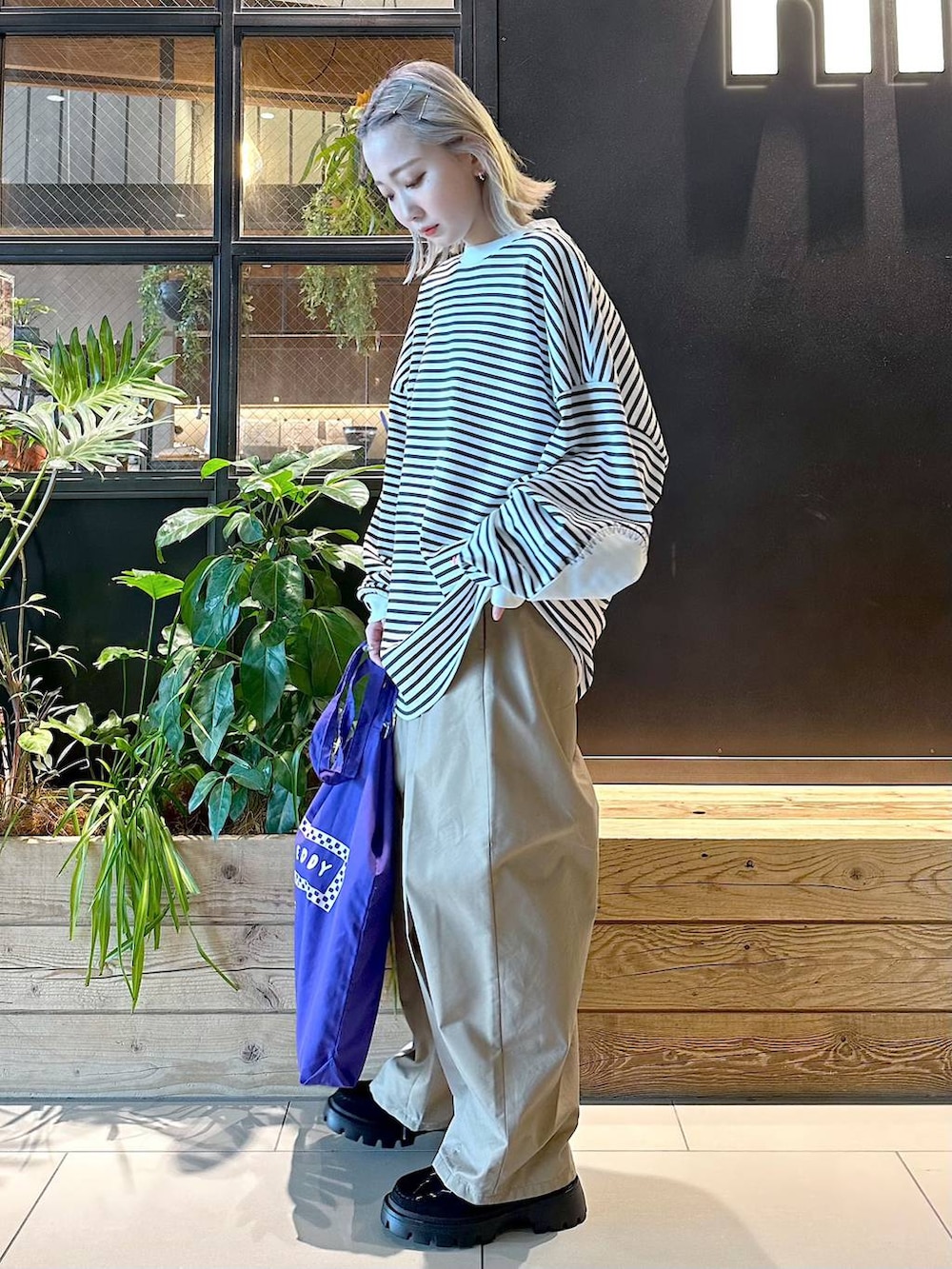 パープル系のトートバッグ、イエロー系のチノパンツ、ブラック系のモカシン/デッキシューズを着用したレディースの秋コーディネートの2枚目の写真