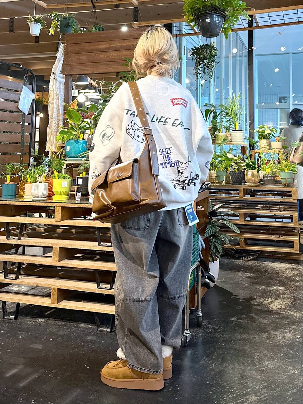 ブラウン系のデニムパンツ、イエロー系のモカシン/デッキシューズ、ブラウン系のショルダーバッグを着用したレディースの秋コーディネートの3枚目の写真