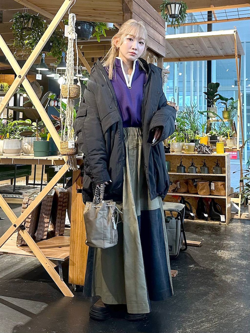 ブラック系のブルゾン、ブラウン系のブーツ、パープル系のスウェットを着用したレディースの冬コーディネートの5枚目の写真