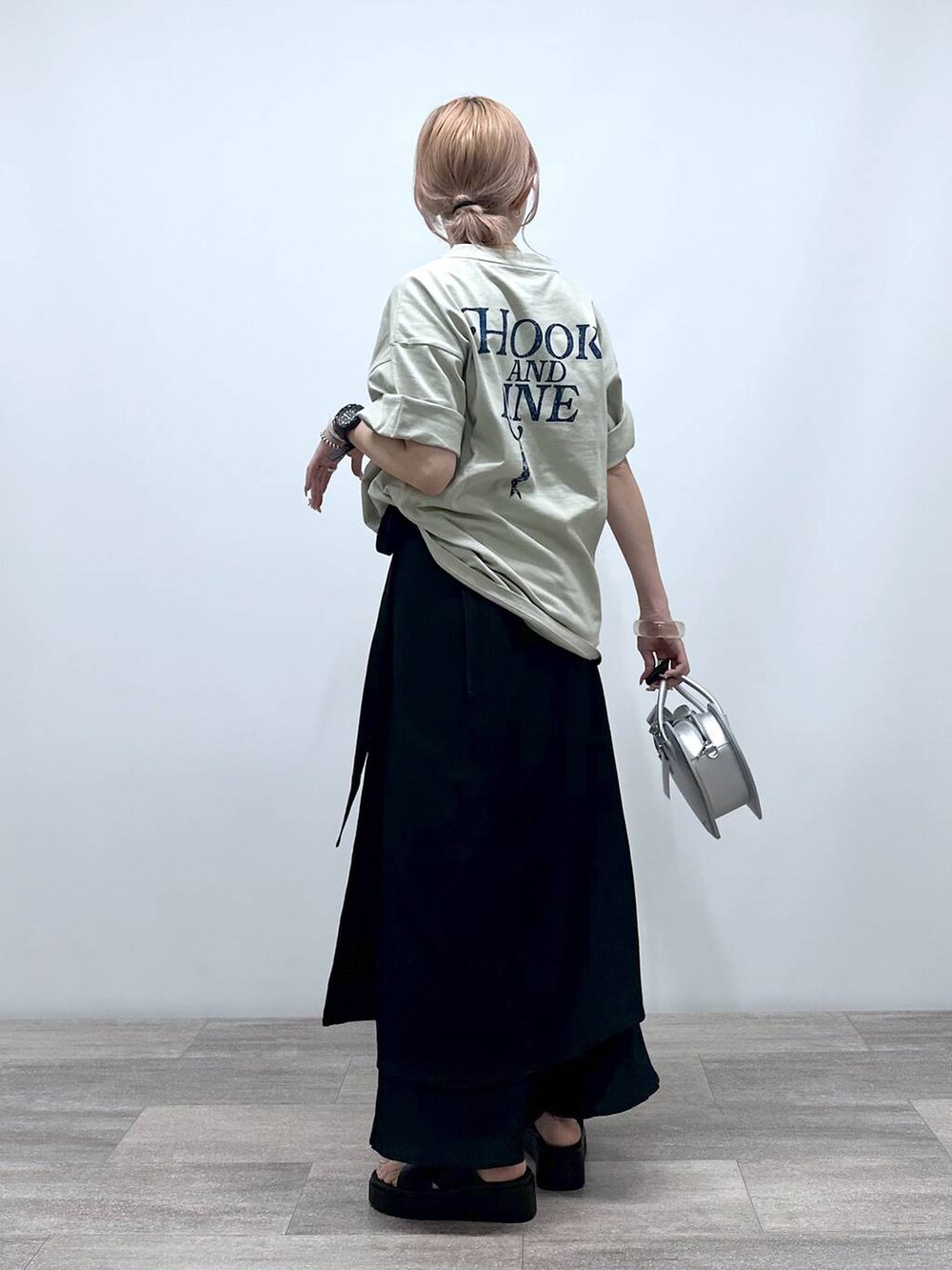 シルバー系のショルダーバッグ、ベージュ系のTシャツ/カットソー、ブラック系のサンダルを着用したレディースの夏コーディネートの3枚目の写真