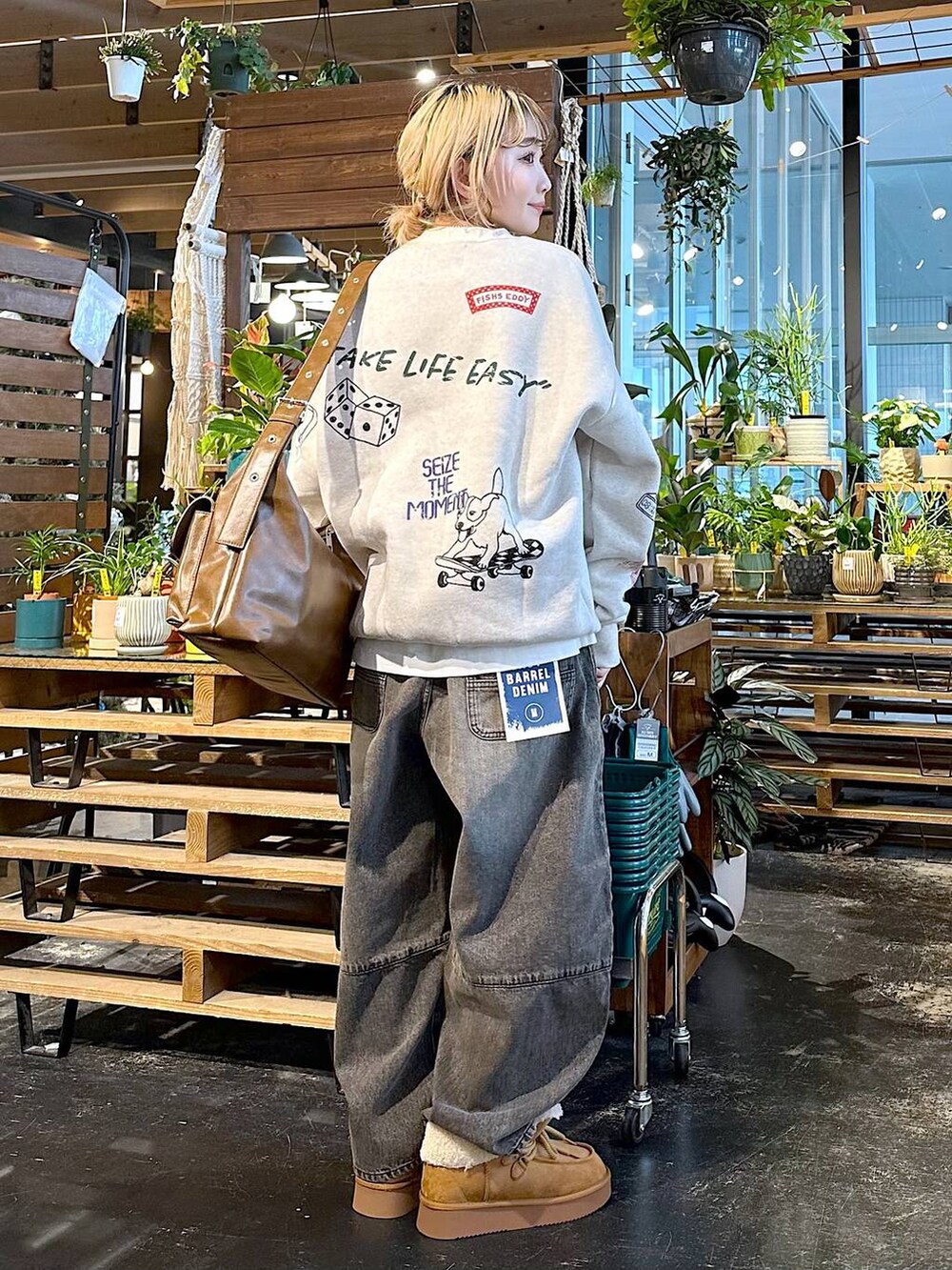 ブラウン系のデニムパンツ、イエロー系のモカシン/デッキシューズ、ブラウン系のショルダーバッグを着用したレディースの秋コーディネートの2枚目の写真