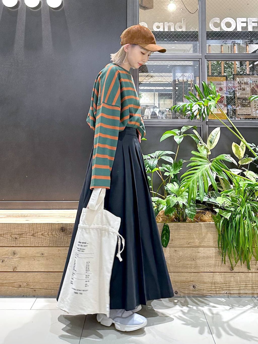 グレー系のスニーカー、グリーン系のTシャツ/カットソー、ベージュ系のトートバッグを着用したレディースの秋コーディネートの3枚目の写真