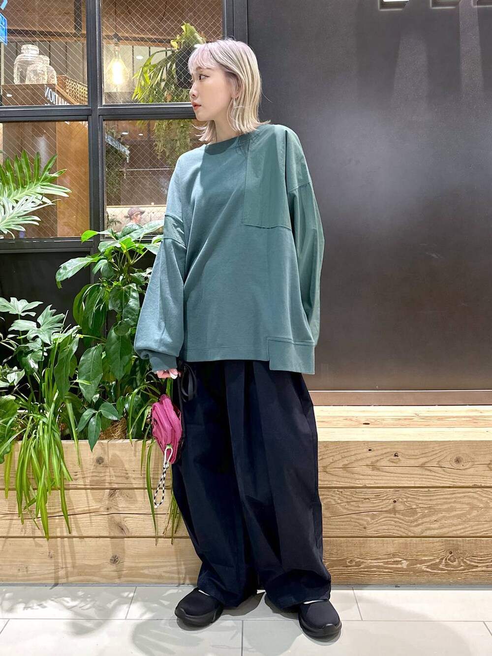 パープル系のショルダーバッグ、グリーン系のスウェット、ブルー系のチノパンツを着用したレディースの秋コーディネートの3枚目の写真