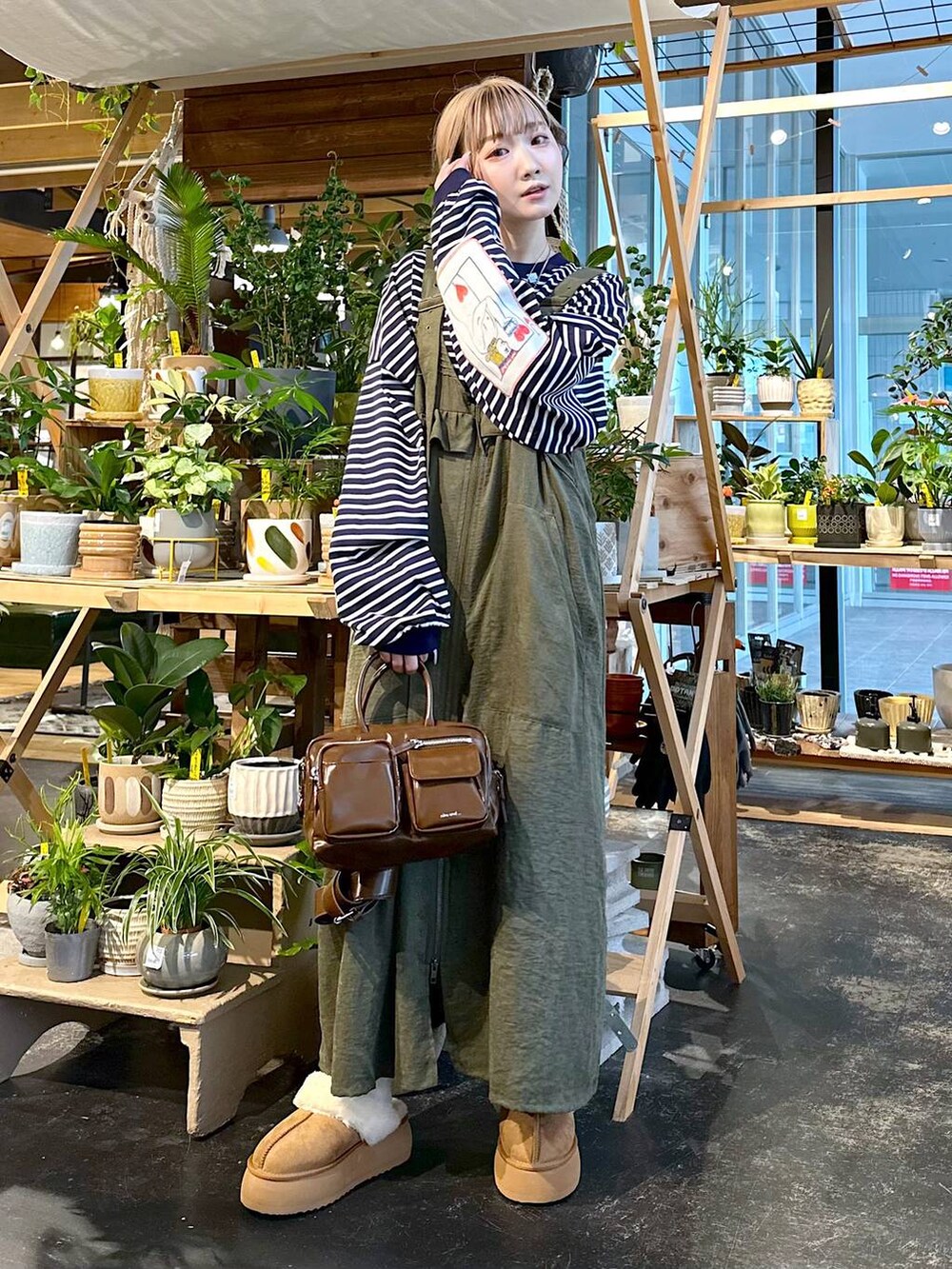 グリーン系のジャンパースカート、その他のTシャツ/カットソー、ブラウン系のショルダーバッグを着用したレディースの秋コーディネートの2枚目の写真
