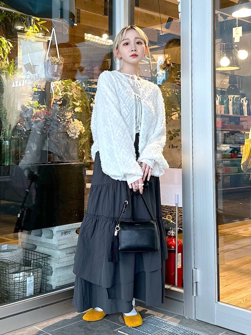 イエロー系のパンプス、ブラック系のショルダーバッグ、ブラック系のスカートを着用したレディースの秋コーディネートの2枚目の写真