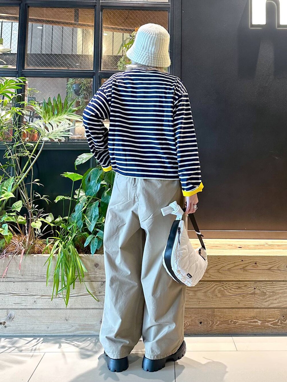 イエロー系のチノパンツ、ブラック系のモカシン/デッキシューズ、ベージュ系のショルダーバッグを着用したレディースの秋コーディネートの3枚目の写真