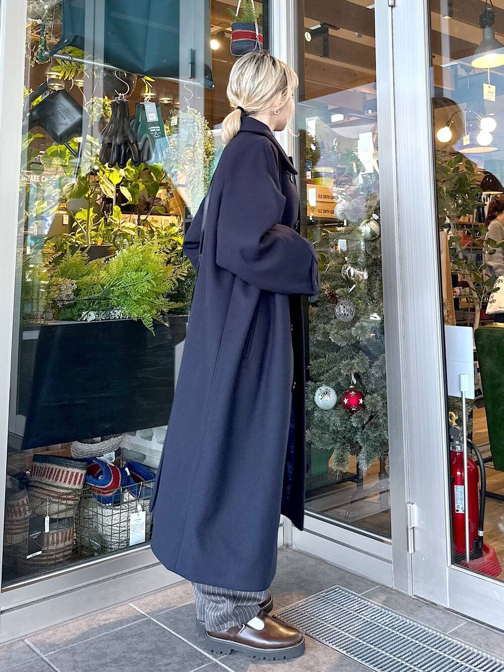 ブルー系のステンカラーコート、ブラウン系のその他シューズ、ブラック系のショルダーバッグを着用したレディースの秋コーディネートの3枚目の写真