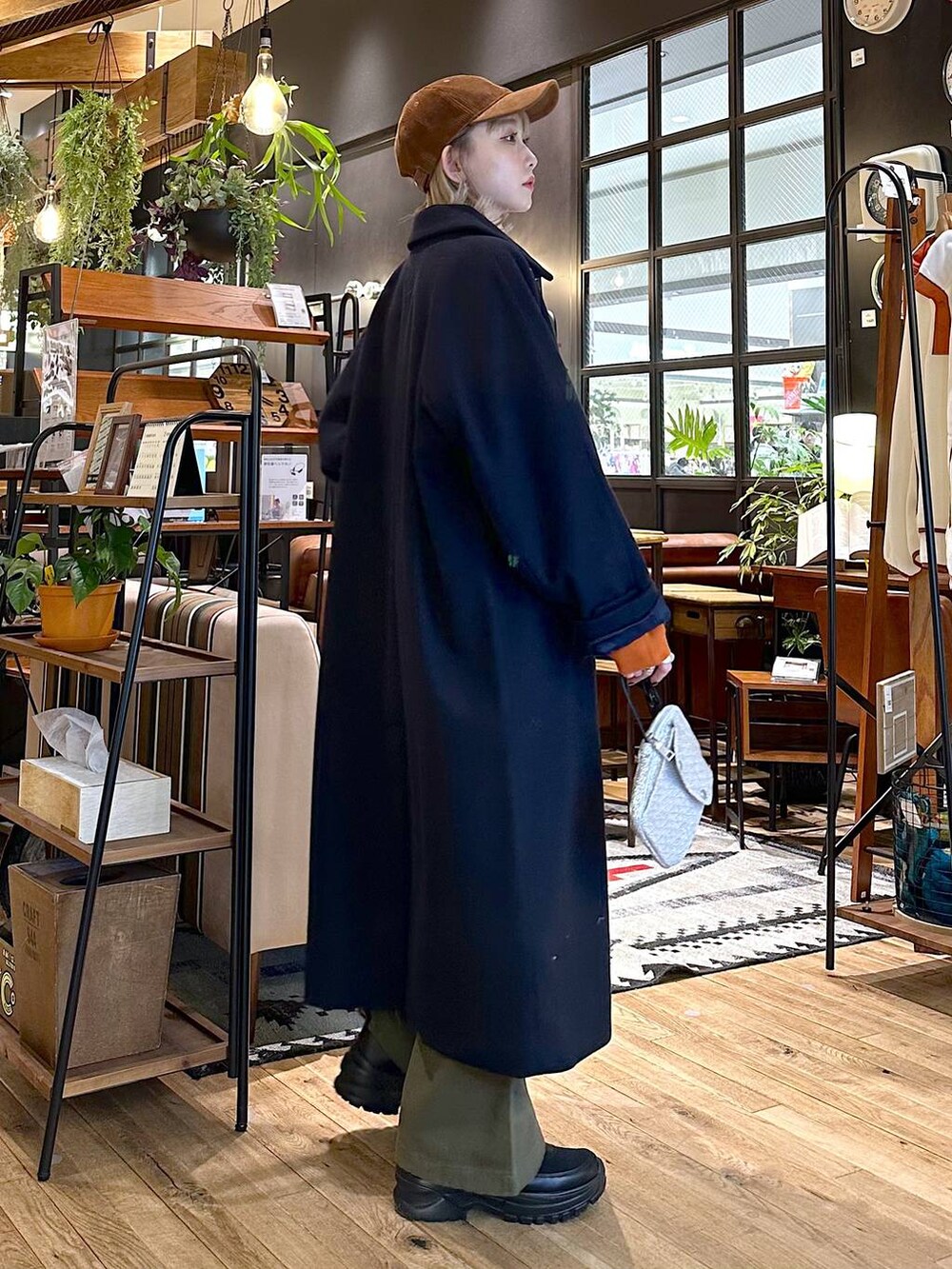 ブルー系のステンカラーコート、ブラック系のブーツ、グリーン系のその他パンツを着用したレディースの冬コーディネートの3枚目の写真