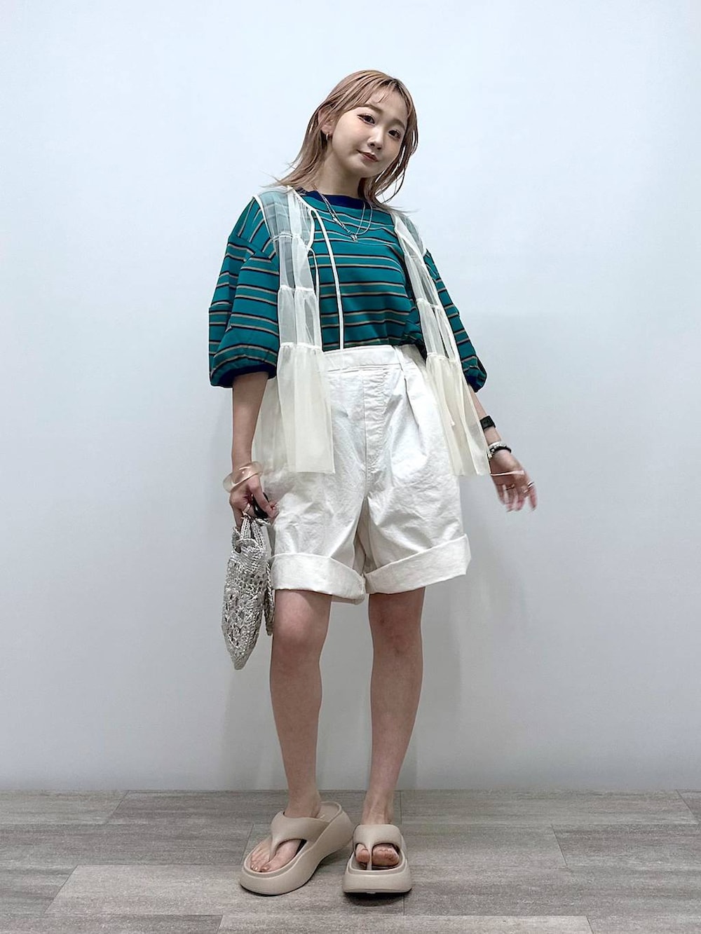 グレー系のショルダーバッグ、ベージュ系のサンダル、グリーン系のTシャツ/カットソーを着用したレディースの夏コーディネートの3枚目の写真