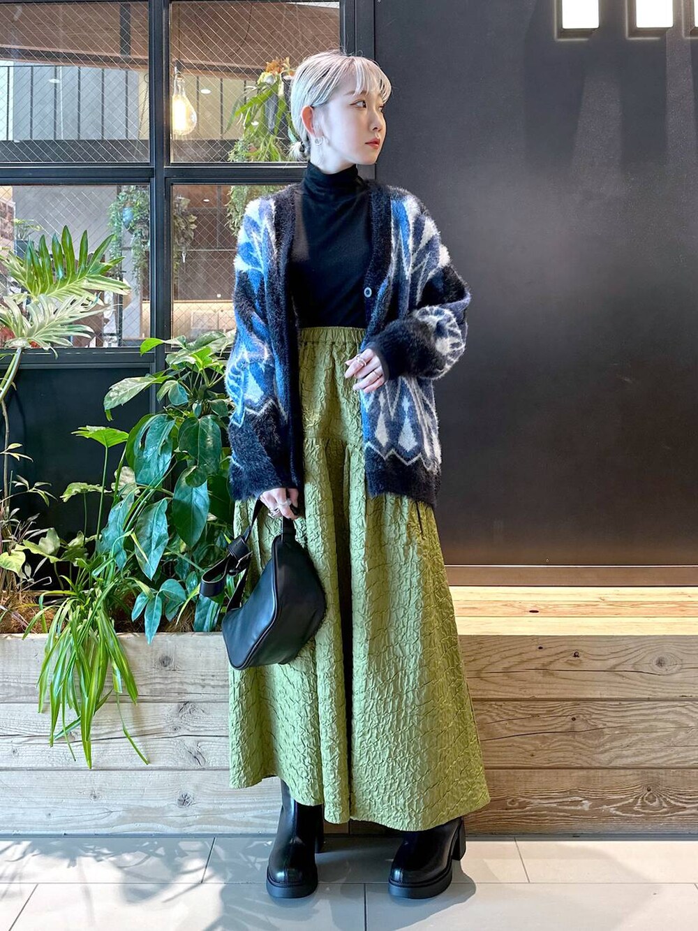 ブラック系のショルダーバッグ、ブラック系のTシャツ/カットソー、グリーン系のスカートを着用したレディースの秋コーディネートの4枚目の写真