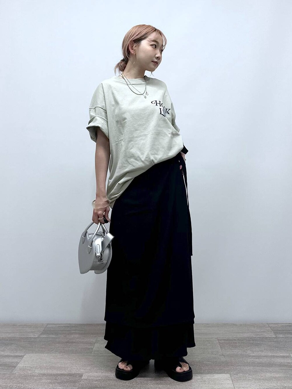 シルバー系のショルダーバッグ、ベージュ系のTシャツ/カットソー、ブラック系のサンダルを着用したレディースの夏コーディネートの2枚目の写真