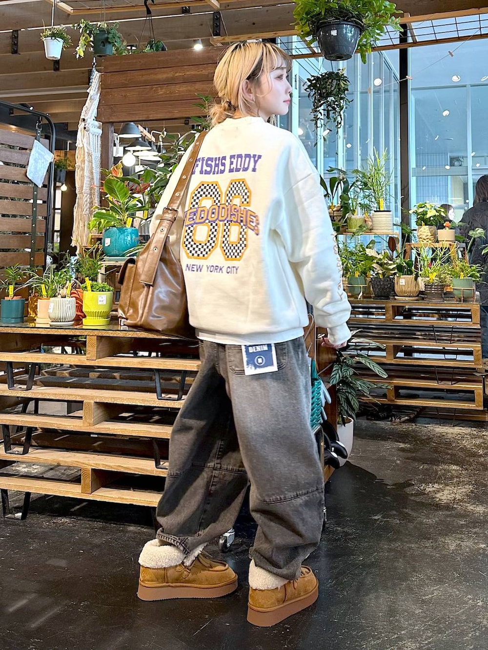 ブラウン系のデニムパンツ、イエロー系のモカシン/デッキシューズ、ブラウン系のショルダーバッグを着用したレディースの秋コーディネートの2枚目の写真