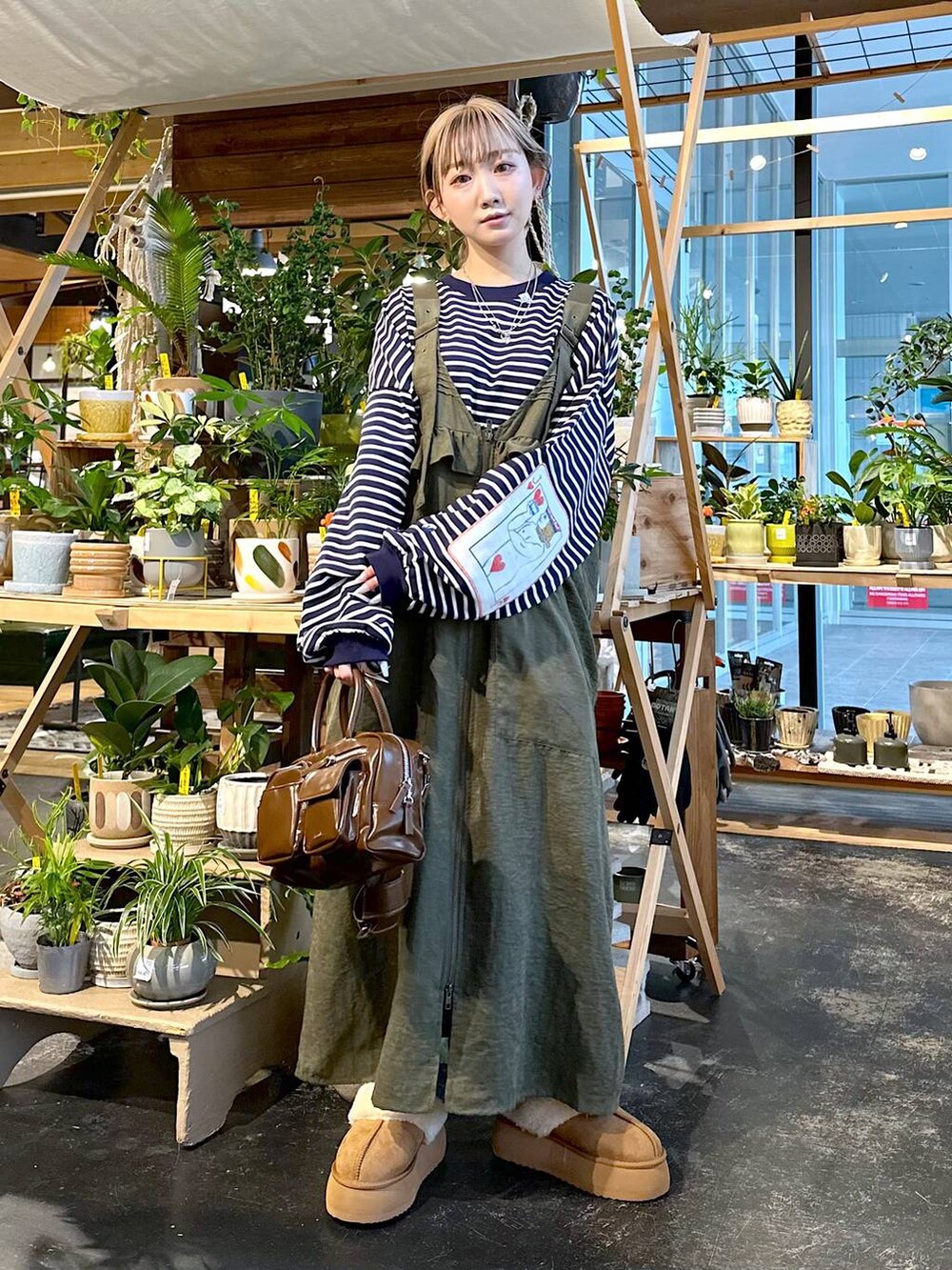 グリーン系のジャンパースカート、その他のTシャツ/カットソー、ブラウン系のショルダーバッグを着用したレディースの秋コーディネートの5枚目の写真