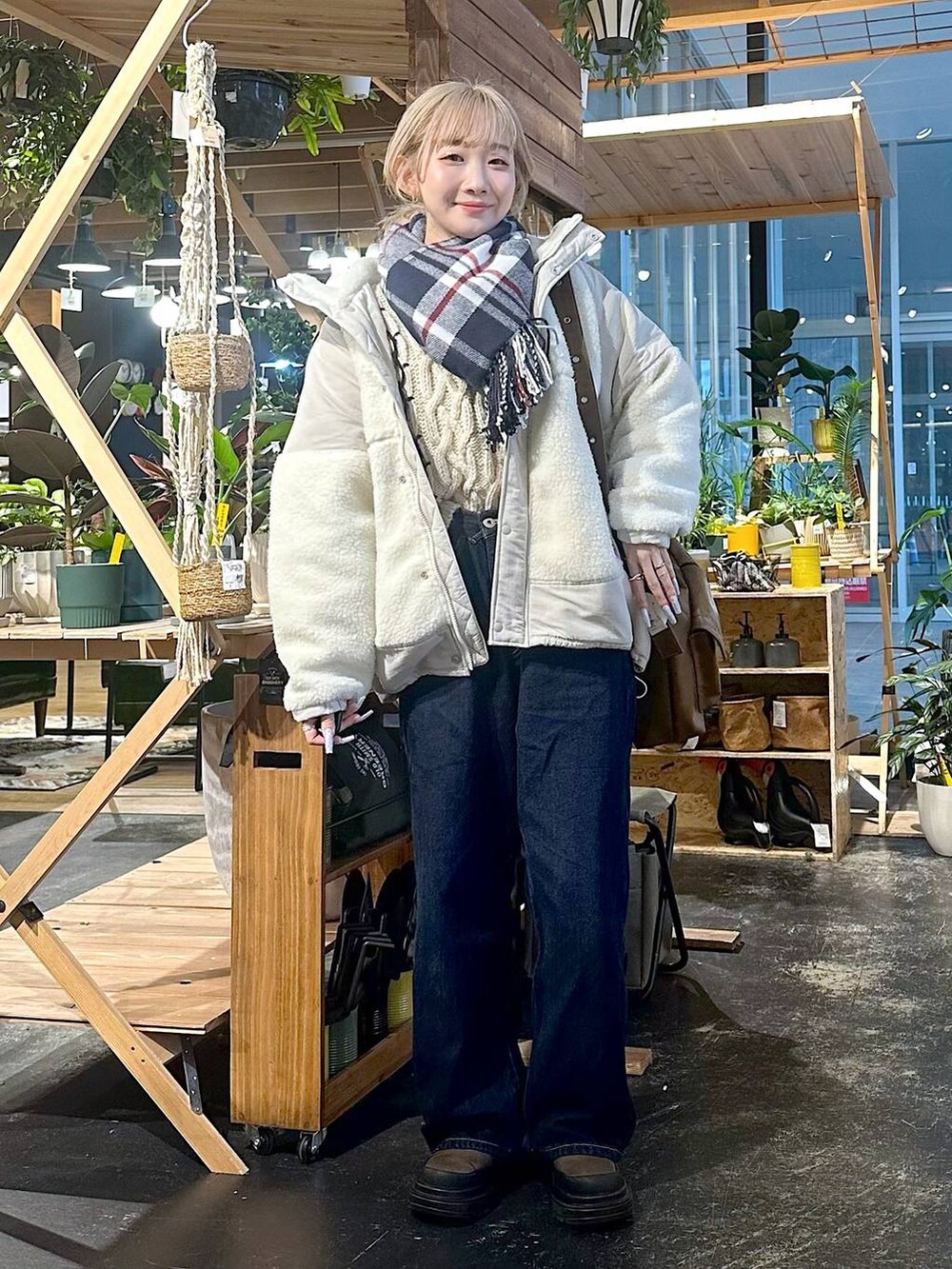 ベージュ系のブルゾン、ブルー系のデニムパンツ、ブラウン系のブーツを着用したレディースの冬コーディネートの4枚目の写真