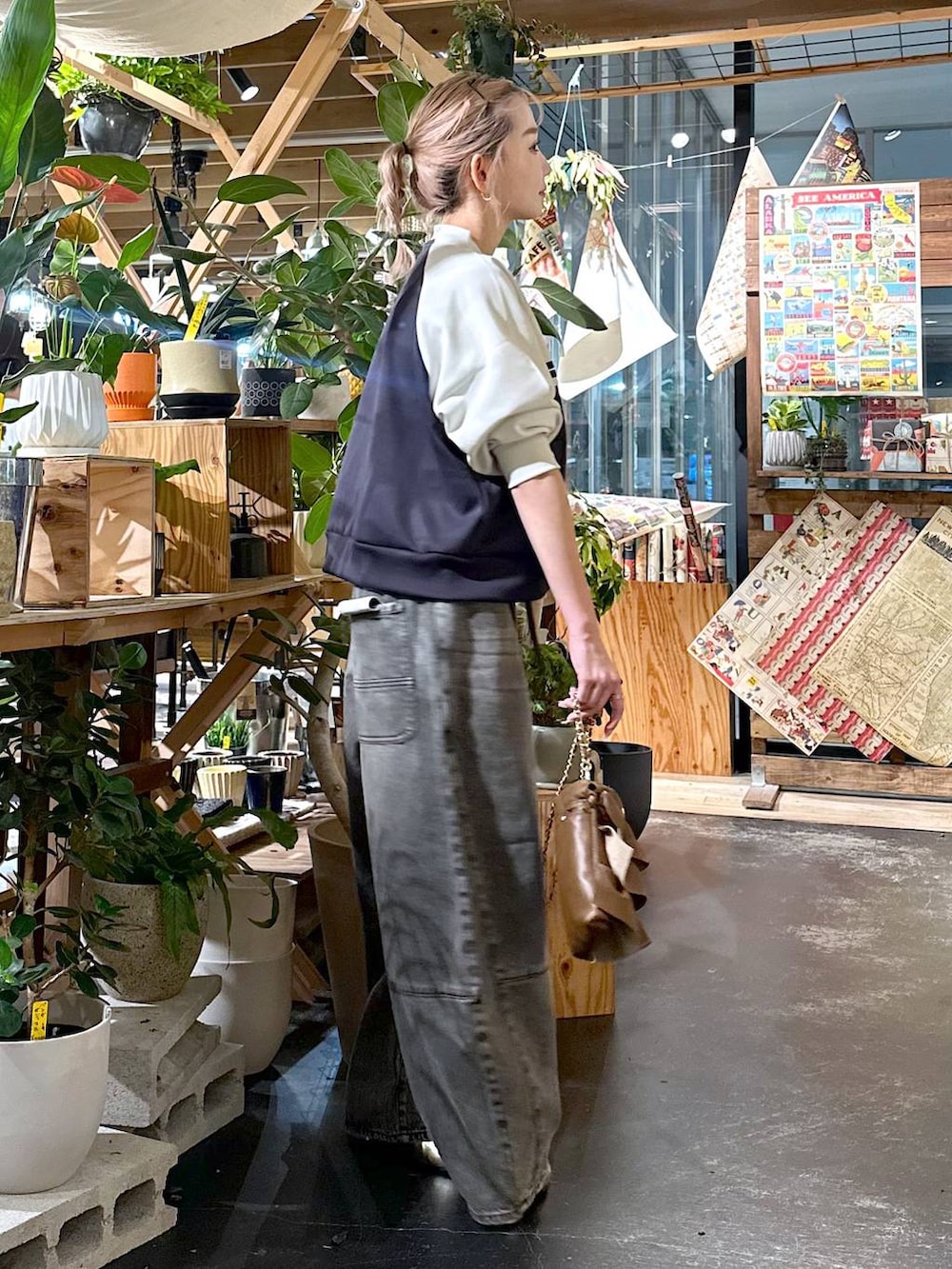 ブラウン系のデニムパンツ、ゴールド系のブーツ、ブラウン系のショルダーバッグを着用したレディースの夏コーディネートの3枚目の写真