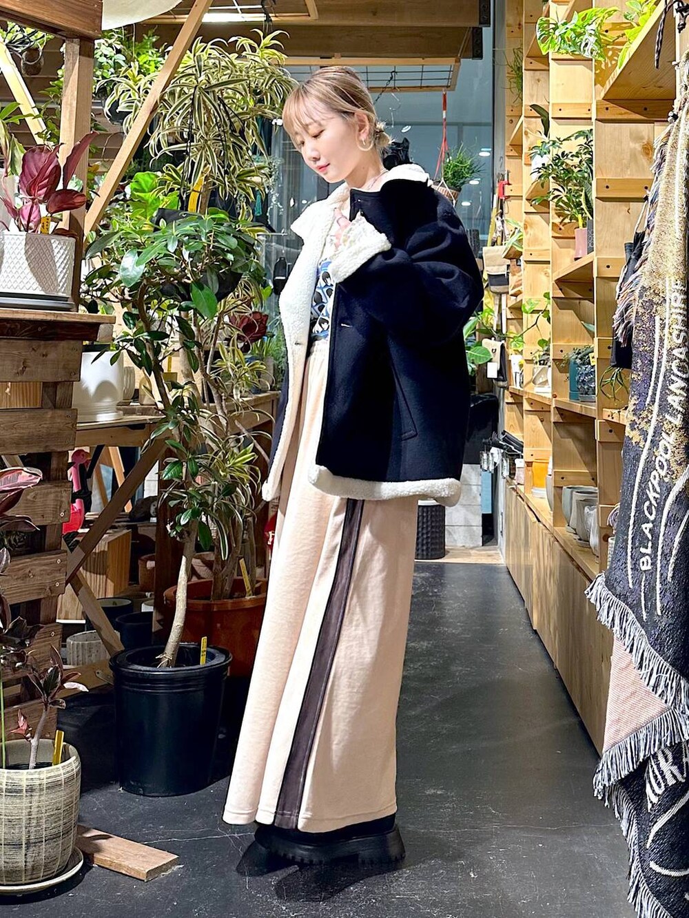 レッド系のショルダーバッグ、ブルー系のブルゾン、ブラック系のブーツを着用したレディースの冬コーディネートの2枚目の写真