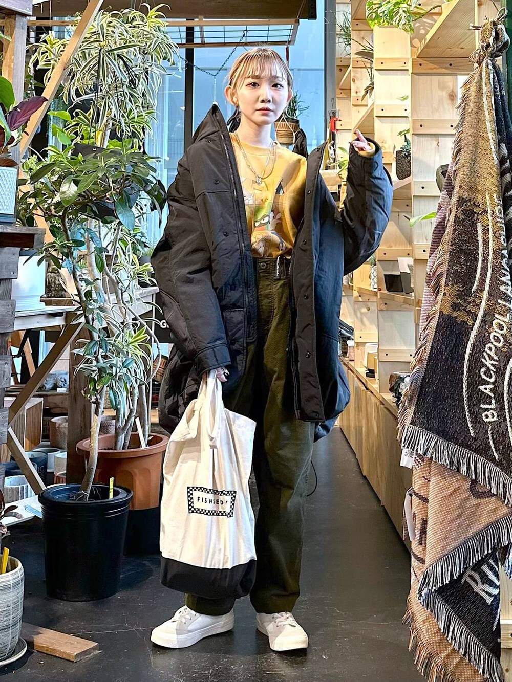 ホワイト系のスニーカー、ブラック系のトートバッグ、その他のブルゾンを着用したレディースの冬コーディネートの2枚目の写真