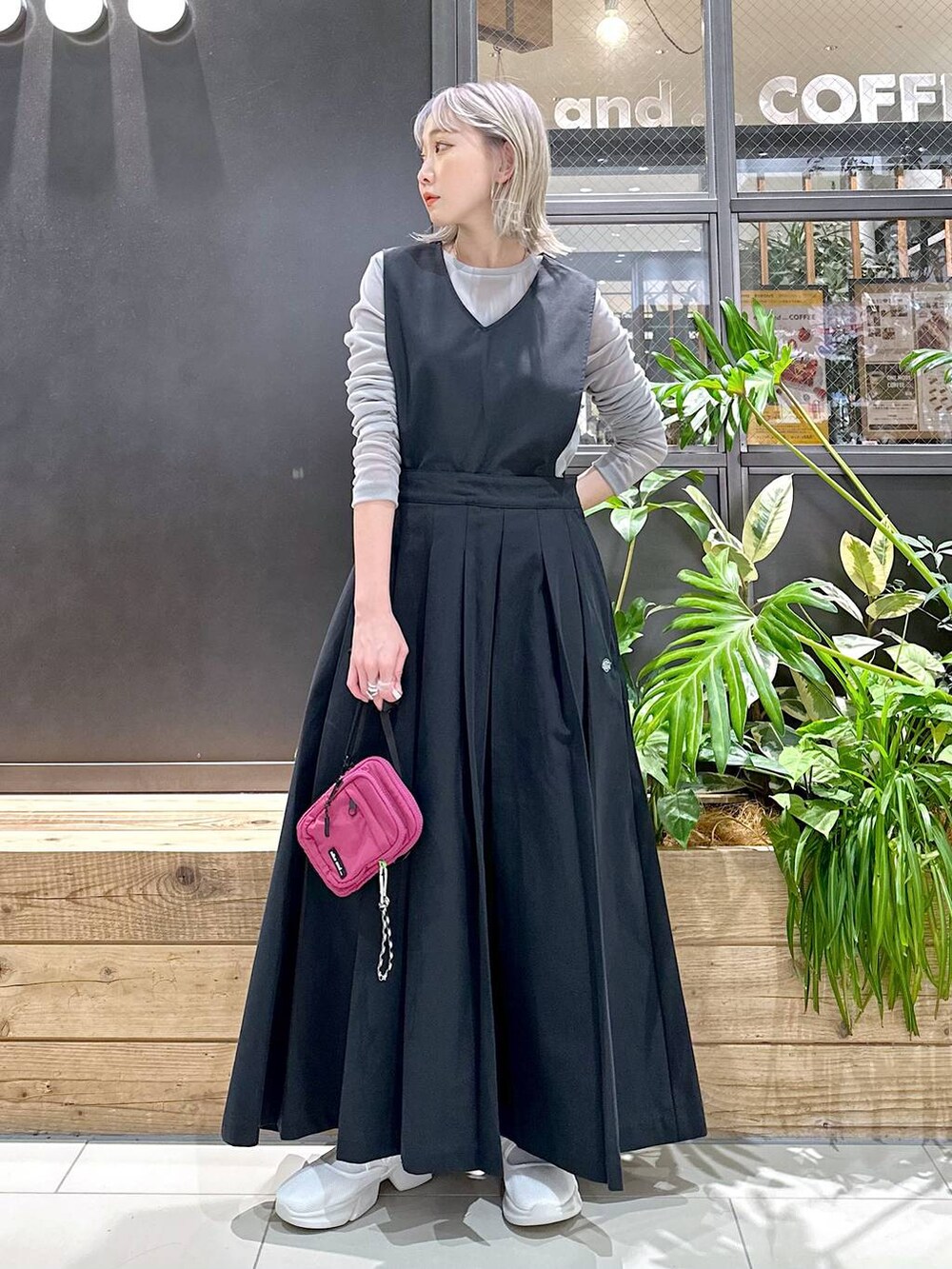 パープル系のショルダーバッグ、ベージュ系のスニーカー、ブラック系のジャンパースカートを着用したレディースの秋コーディネートの3枚目の写真