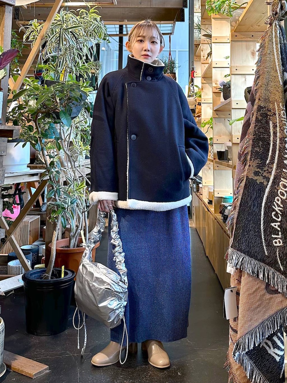 ブルー系のブルゾン、ベージュ系のブーツ、グレー系のショルダーバッグを着用したレディースの冬コーディネートの2枚目の写真