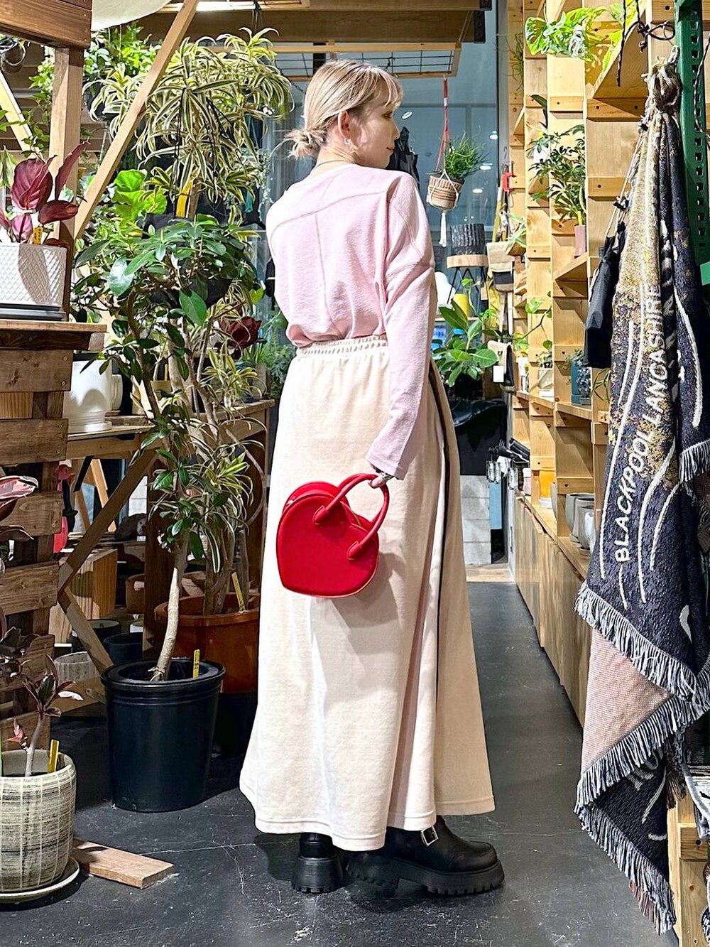 レッド系のショルダーバッグ、ブラック系のブーツ、ベージュ系のスカートを着用したレディースの冬コーディネートの2枚目の写真