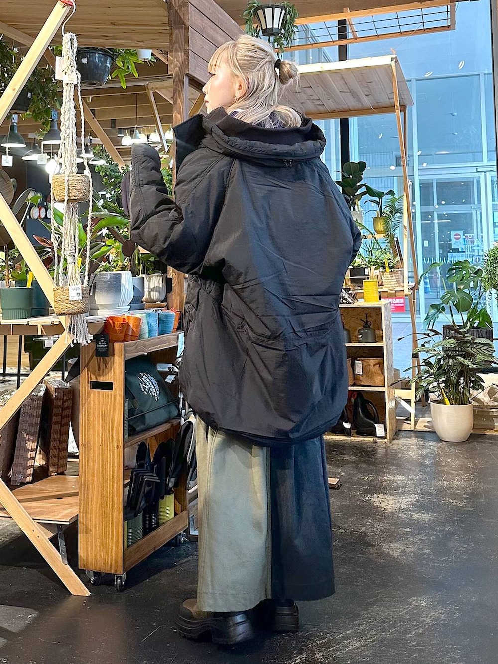 ブラック系のブルゾン、ブラウン系のブーツ、パープル系のスウェットを着用したレディースの冬コーディネートの3枚目の写真