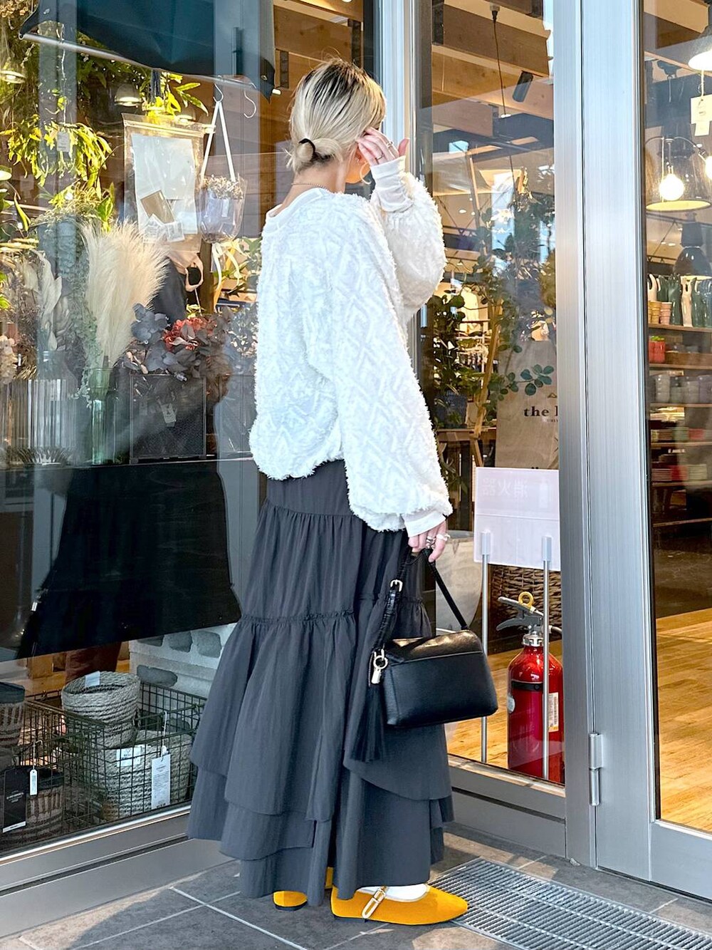 イエロー系のパンプス、ブラック系のショルダーバッグ、ブラック系のスカートを着用したレディースの秋コーディネートの3枚目の写真