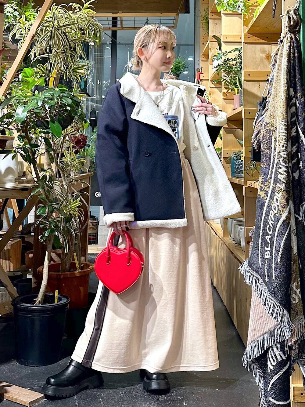 レッド系のショルダーバッグ、ブルー系のブルゾン、ブラック系のブーツを着用したレディースの冬コーディネートの4枚目の写真