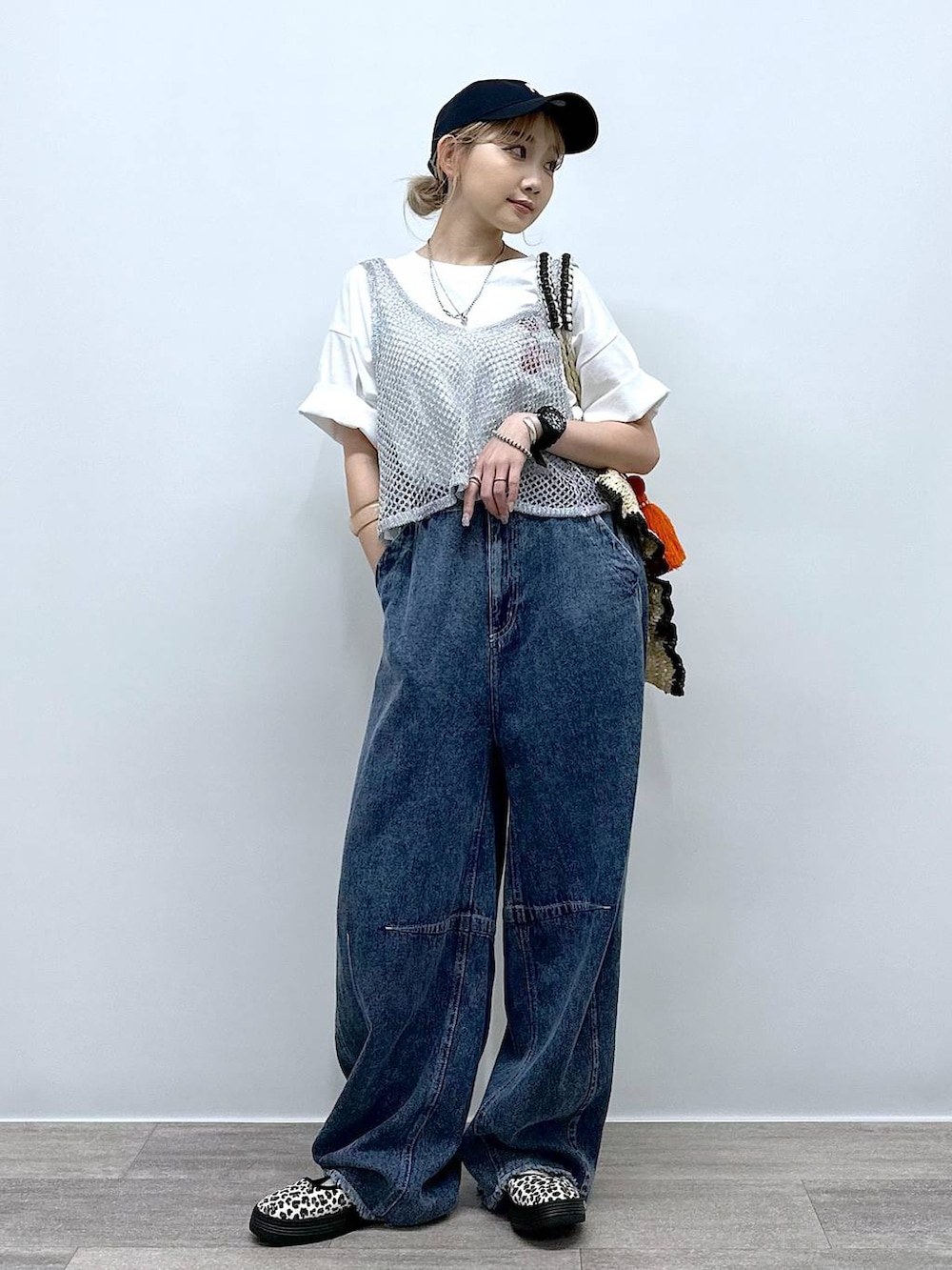 ベージュ系のトートバッグ、その他のスニーカー、ブルー系のデニムパンツを着用したレディースの夏コーディネートの2枚目の写真