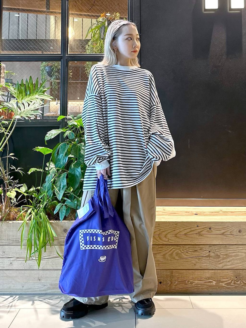 パープル系のトートバッグ、イエロー系のチノパンツ、ブラック系のモカシン/デッキシューズを着用したレディースの秋コーディネートの5枚目の写真