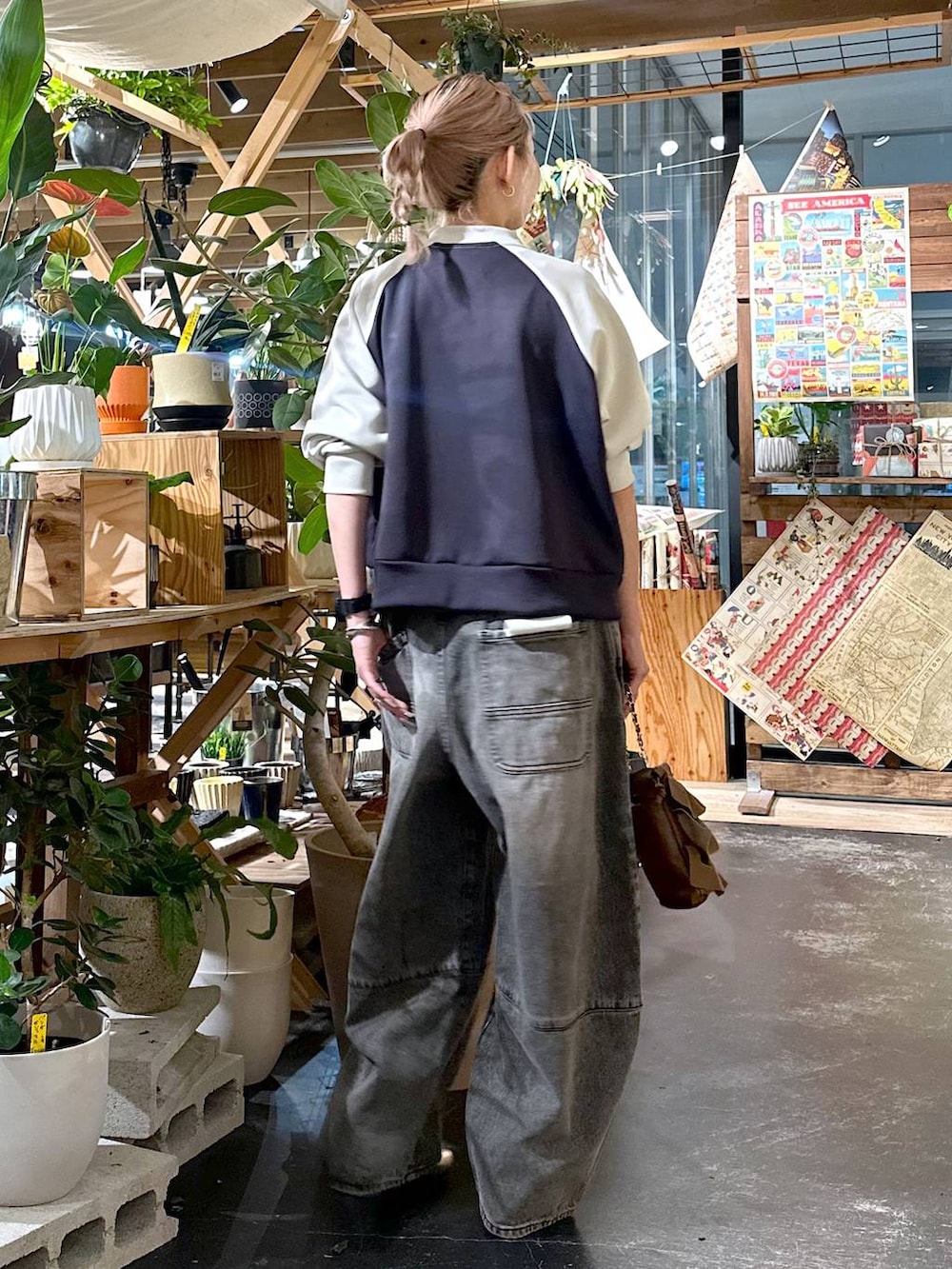 ブラウン系のデニムパンツ、ゴールド系のブーツ、ブラウン系のショルダーバッグを着用したレディースの夏コーディネートの2枚目の写真