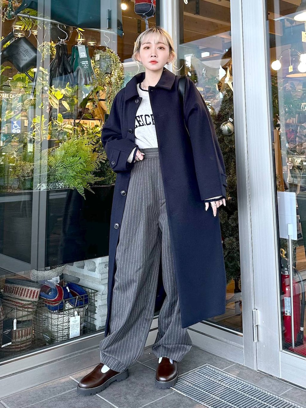 ブルー系のステンカラーコート、ブラウン系のその他シューズ、ブラック系のショルダーバッグを着用したレディースの秋コーディネートの2枚目の写真