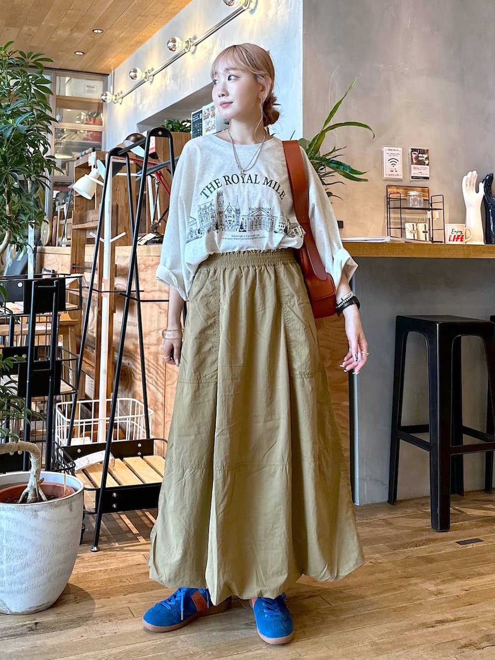 ベージュ系のTシャツ/カットソー、ブラウン系のショルダーバッグ、ブルー系のスニーカーを着用したレディースの夏コーディネートの2枚目の写真