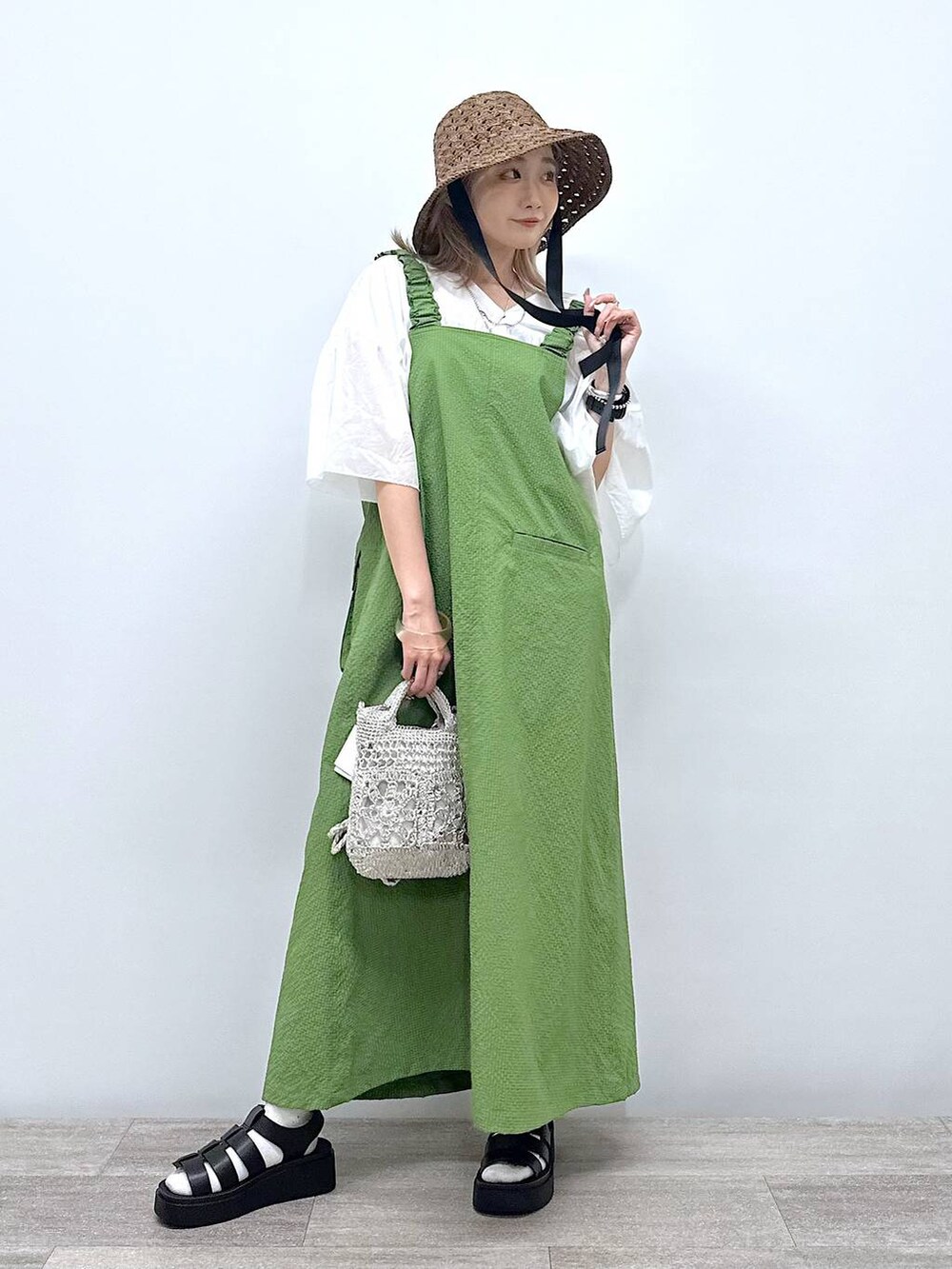 グレー系のショルダーバッグ、ブラック系のサンダル、グリーン系のジャンパースカートを着用したレディースの夏コーディネートの6枚目の写真