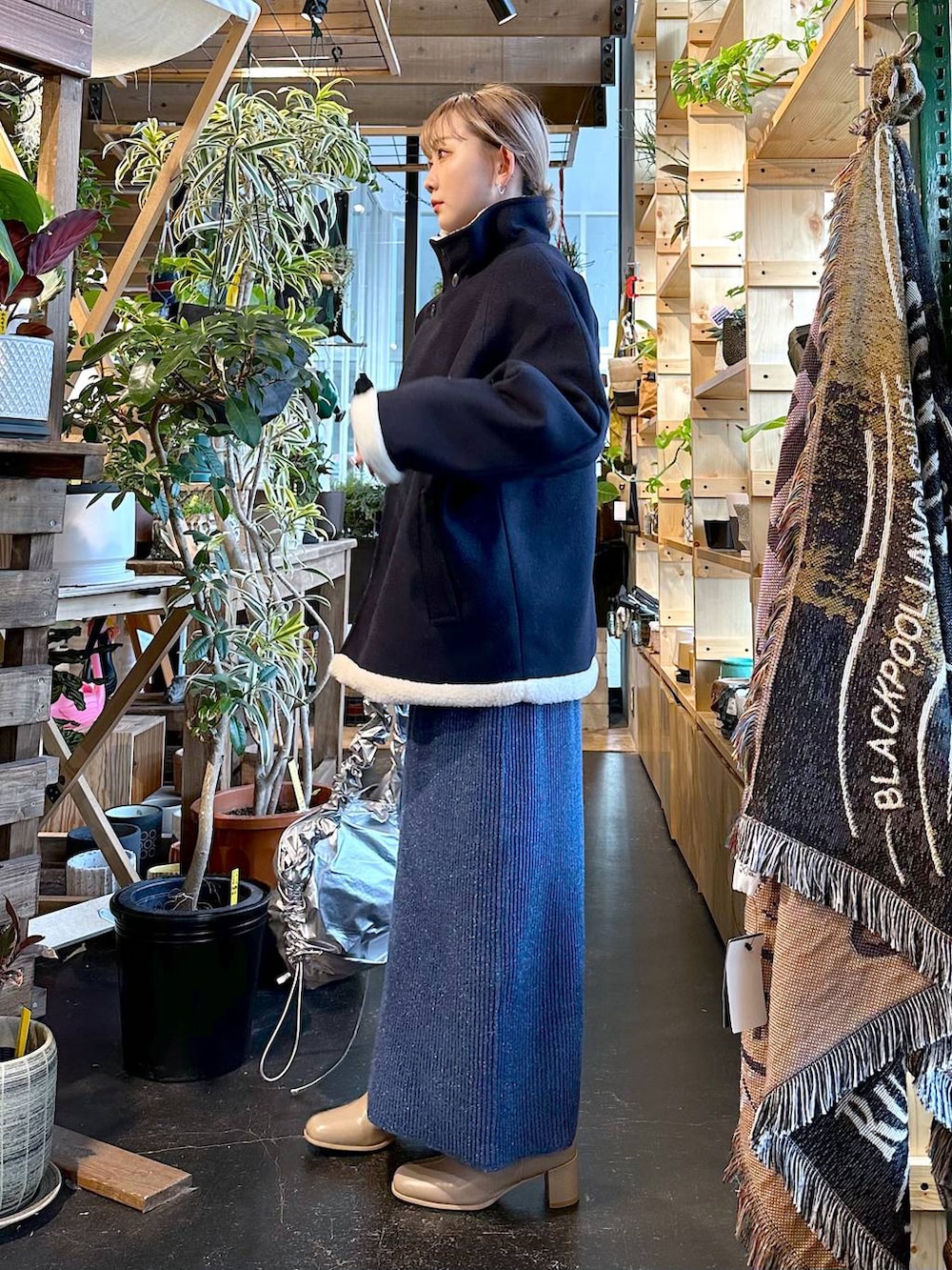 ブルー系のブルゾン、ベージュ系のブーツ、グレー系のショルダーバッグを着用したレディースの冬コーディネートの3枚目の写真