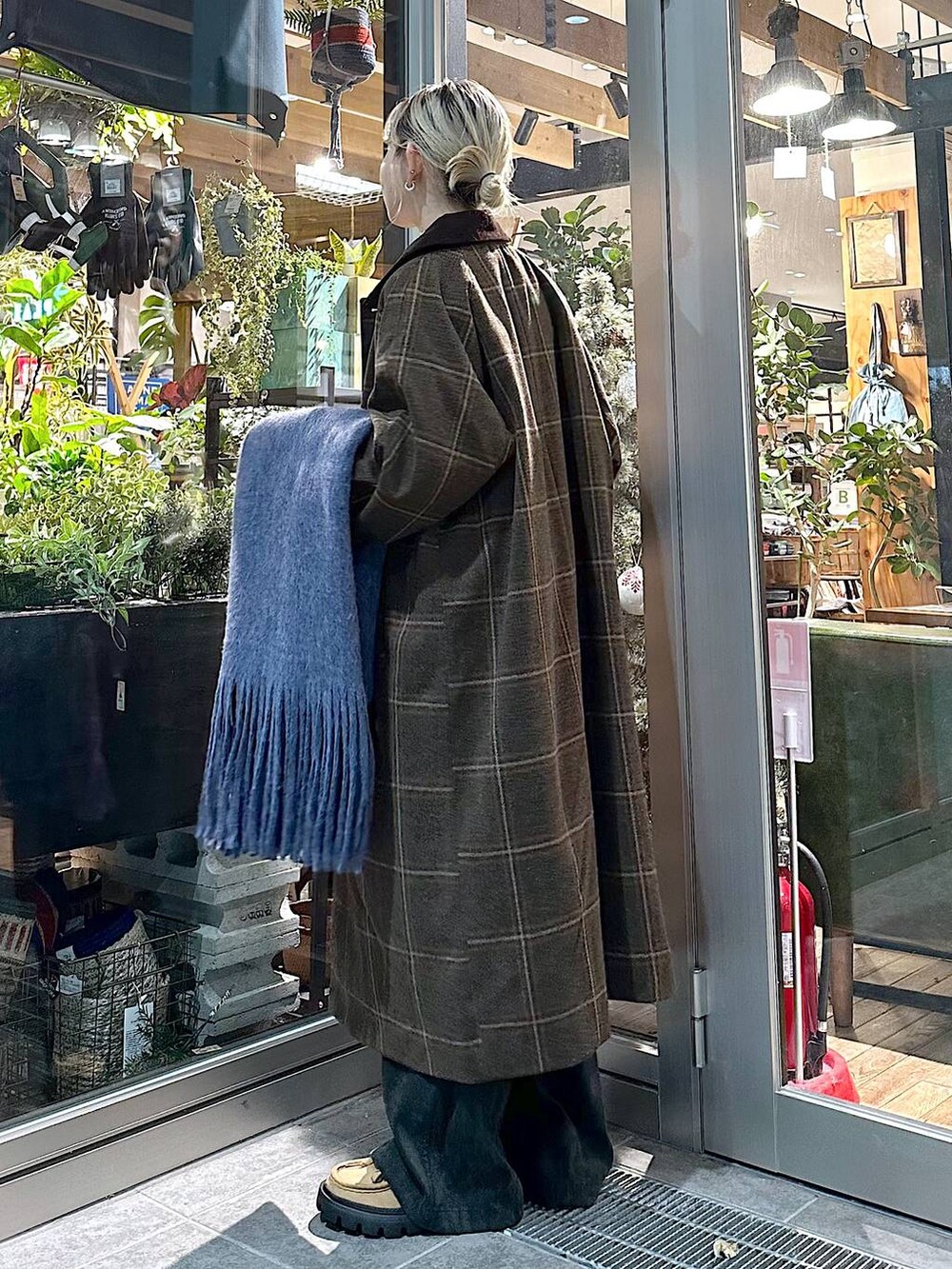 ブラウン系のステンカラーコート、イエロー系のモカシン/デッキシューズ、ブラック系のカーゴパンツを着用したレディースの秋コーディネートの2枚目の写真