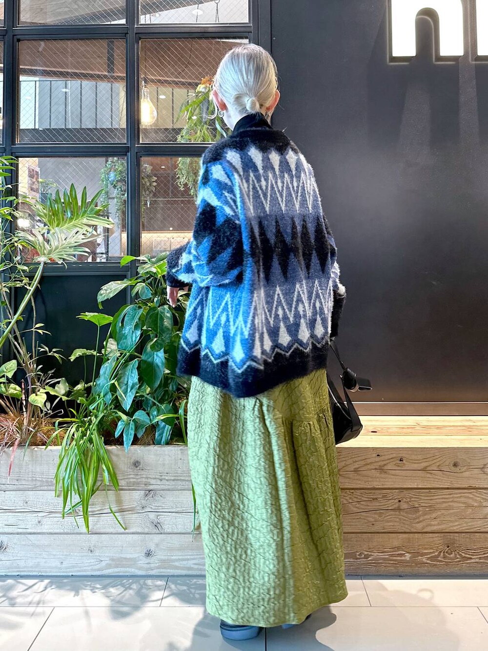 ブラック系のショルダーバッグ、ブラック系のTシャツ/カットソー、グリーン系のスカートを着用したレディースの秋コーディネートの3枚目の写真