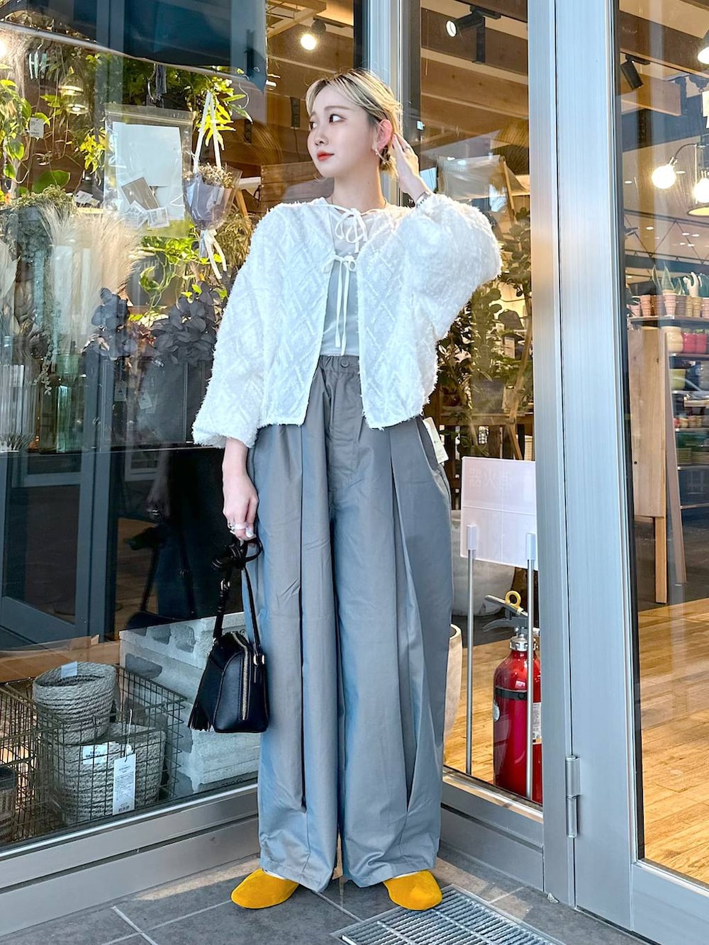 イエロー系のパンプス、グリーン系のチノパンツ、ブラック系のショルダーバッグを着用したレディースの秋コーディネートの3枚目の写真