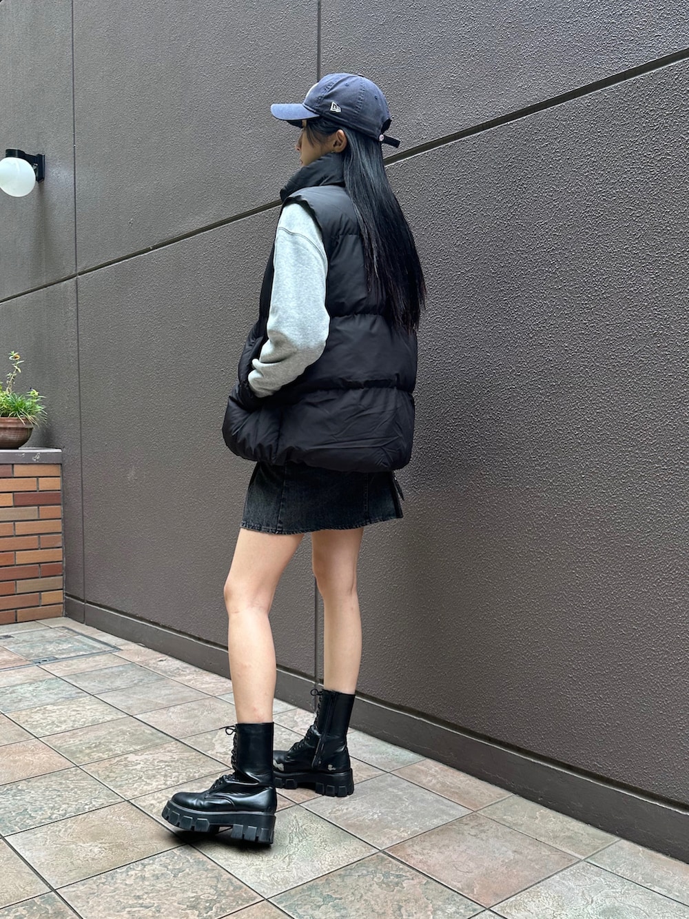グレー系のスウェット、ブラック系のダウンベスト、ブラック系のブーツを着用したレディースの秋コーディネートの2枚目の写真