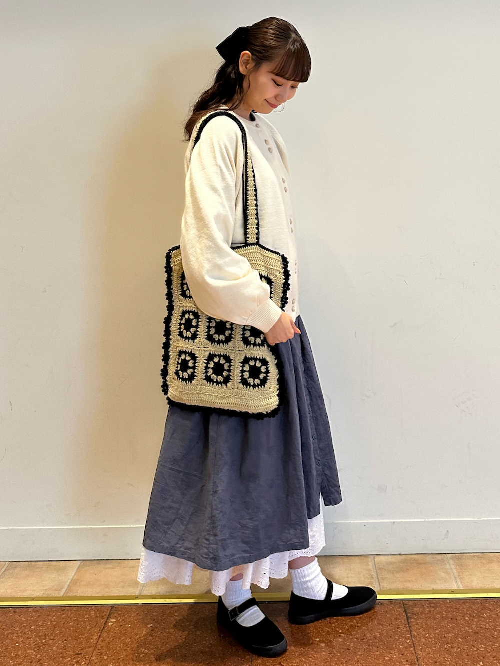 ホワイト系のカーディガン/ボレロ、ベージュ系のハンドバッグ、ブルー系のワンピースを着用したレディースの秋コーディネートの2枚目の写真