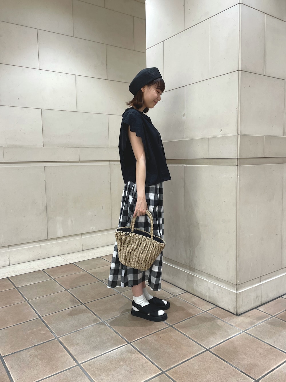 ブラック系のベスト、ブラック系のスカート、ブラック系のかごバッグを着用したレディースの夏コーディネートの2枚目の写真