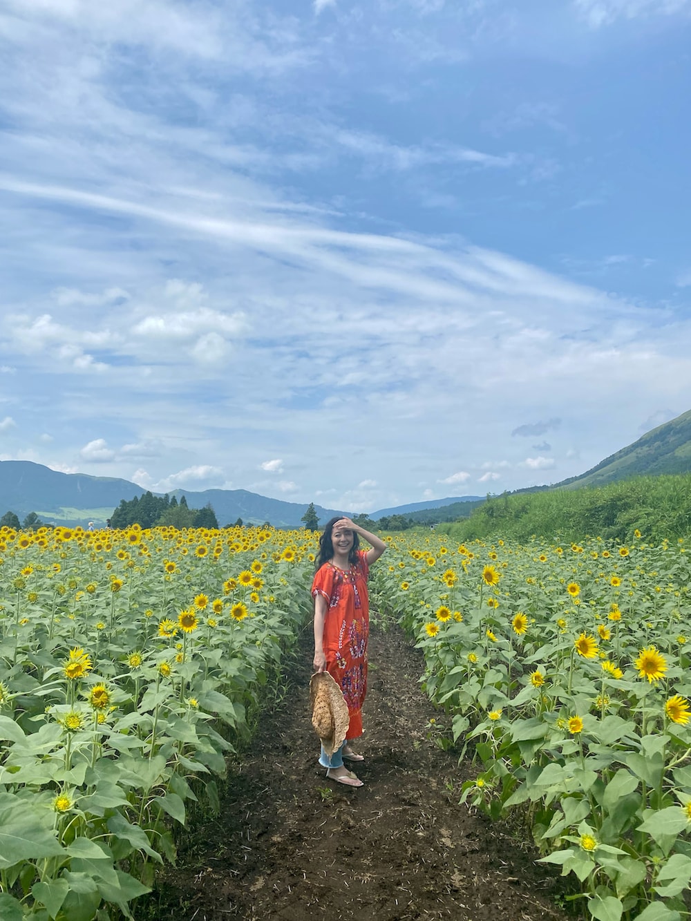 レッド系のワンピース、ブルー系のデニムパンツ、ホワイト系のサンダルを着用したレディースの夏コーディネートの3枚目の写真