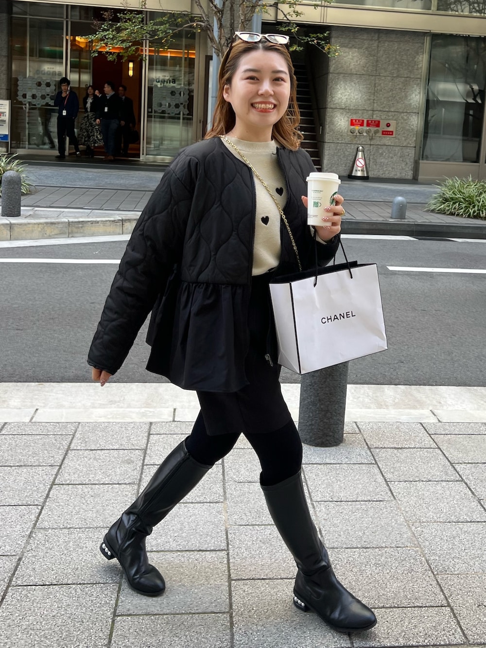 ベージュ系のニット/セーター、ブラック系のダウンジャケット/コート、ブラウン系のショルダーバッグを着用したレディースの秋コーディネートの3枚目の写真