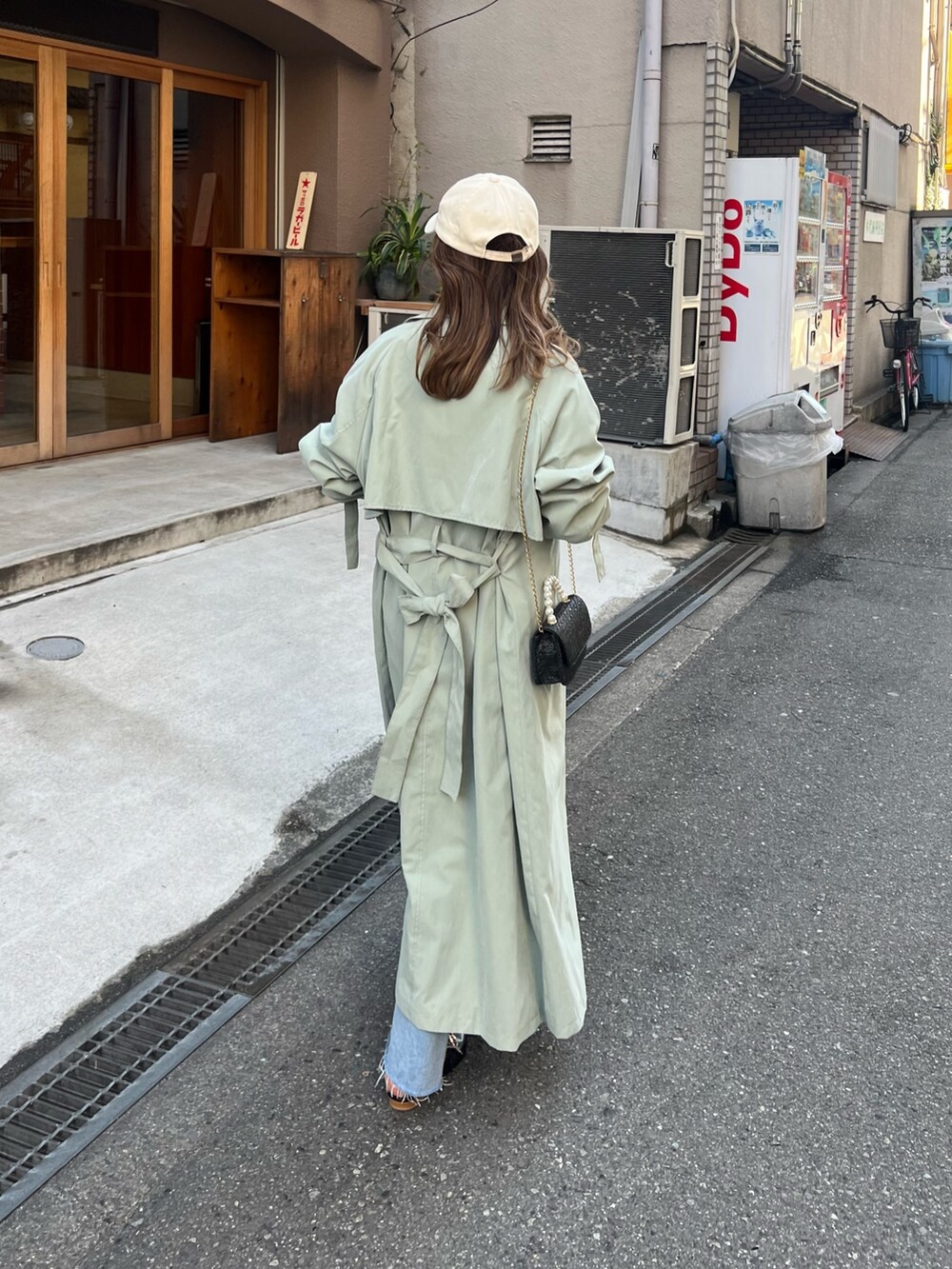 グリーン系のトレンチコート、ブルー系のデニムパンツ、ブラック系のパンプスを着用したレディースの春コーディネートの2枚目の写真