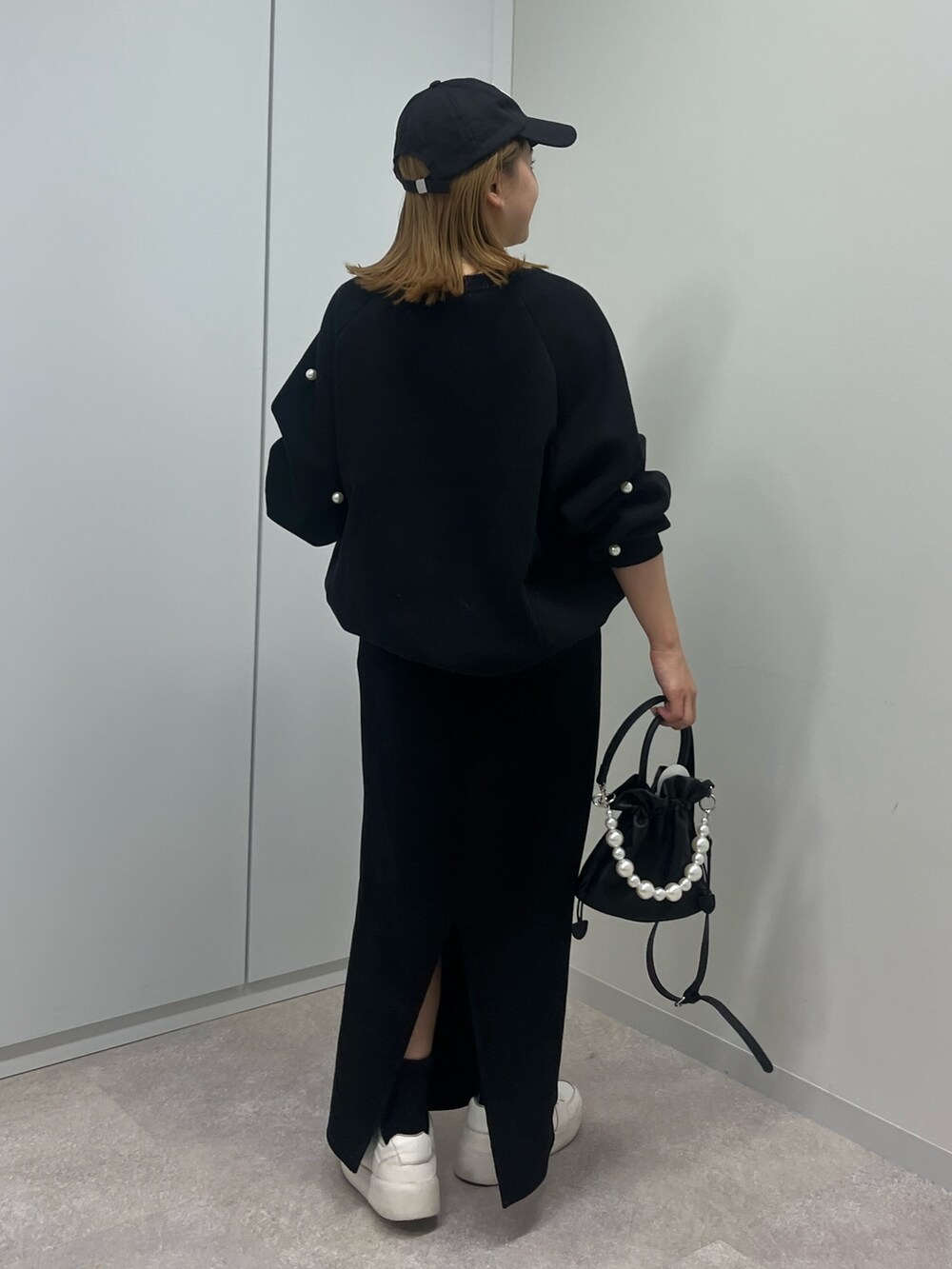 グレー系のスウェット、ブラック系のスカート、ブラック系のショルダーバッグを着用したレディースの秋コーディネートの2枚目の写真