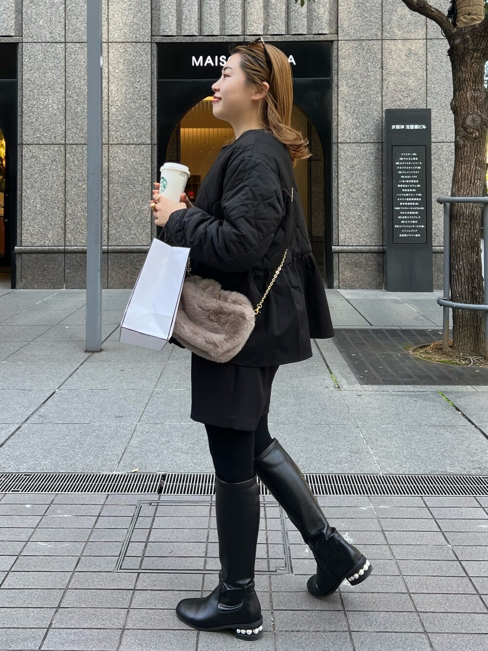 ベージュ系のニット/セーター、ブラック系のダウンジャケット/コート、ブラウン系のショルダーバッグを着用したレディースの秋コーディネートの2枚目の写真