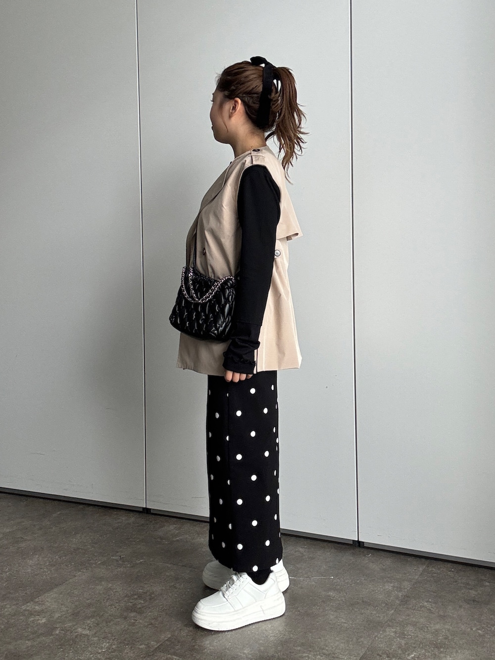 ブラック系のTシャツ/カットソー、ベージュ系のベスト、ブラック系のショルダーバッグを着用したレディースの夏コーディネートの2枚目の写真